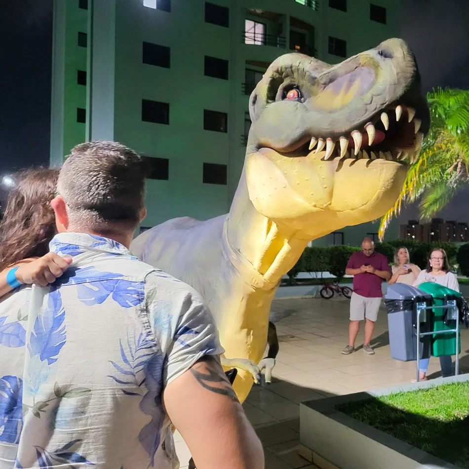 Crianças tirando fotos divertidas com o T-Rex Personagem Vivo e o Velociraptor na festa